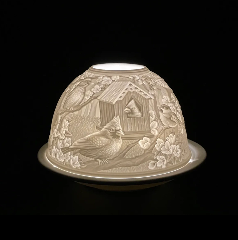 A dome shaped candle holder with a bird and flowers design.