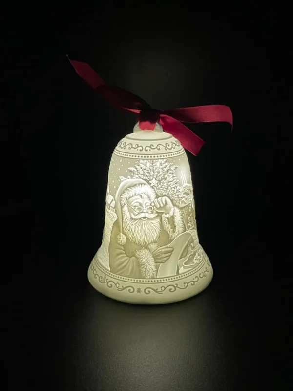 A lighted bell with santa claus and christmas tree.