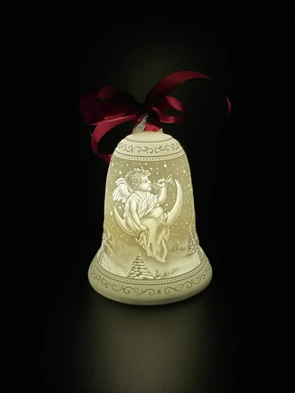 A bell with a bow on it sitting in the dark.