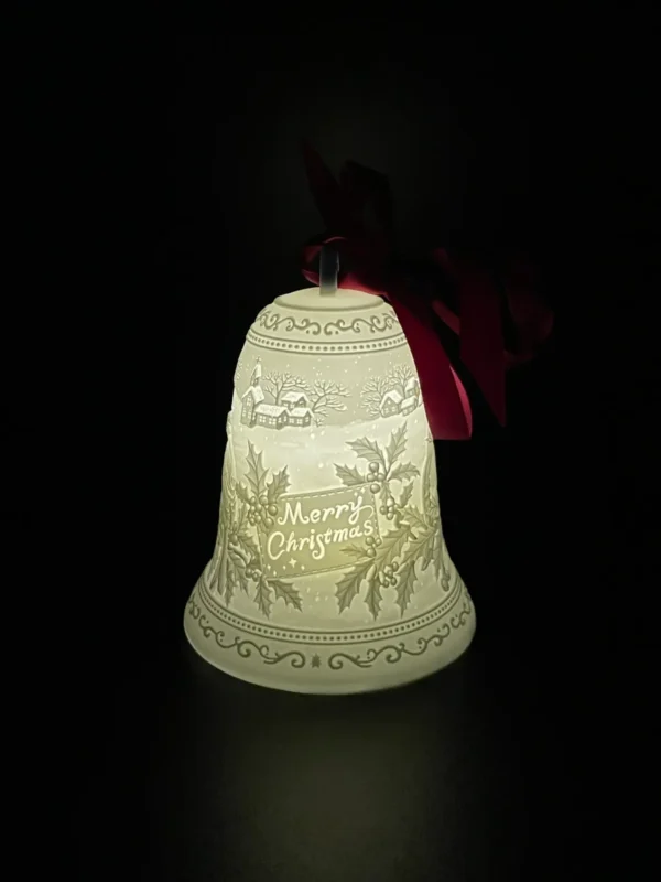 A lighted christmas bell with a bow hanging from it.