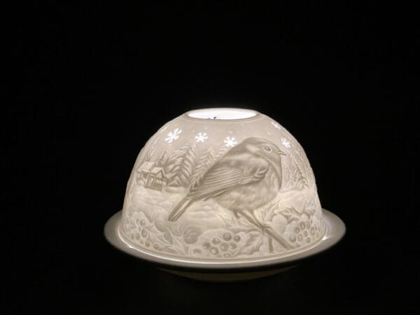 A white bird is sitting on the top of a candle holder.