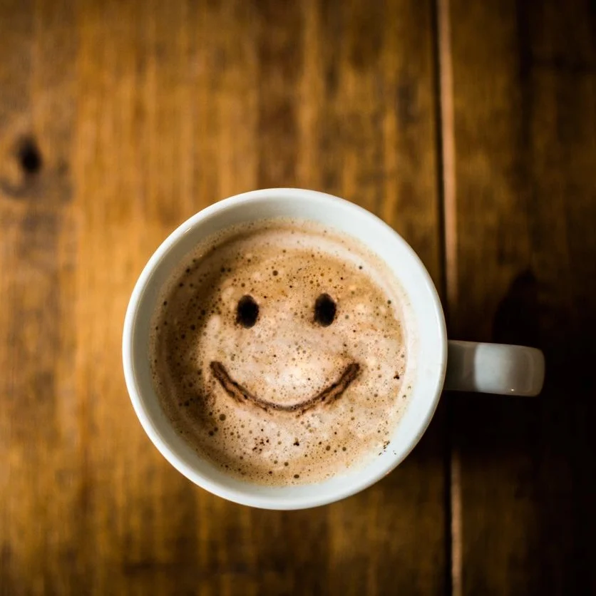 A cup of coffee with a smiley face on it.